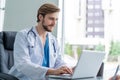 Young male doctor working on laptop computer, sitting in medical office. Royalty Free Stock Photo