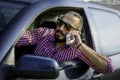 A young male driver talking on a cell phone while driving a car. Royalty Free Stock Photo