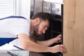 Electrician Repairing Oven With Screwdriver