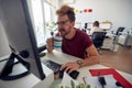 A young male employee is drinking a coffee while working in the office. Employees, job, office Royalty Free Stock Photo