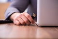 Young male employee inserting flash drive into laptop