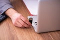 Young male employee inserting flash drive into laptop