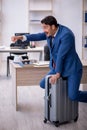 Young male employee preparing for trip at workplace Royalty Free Stock Photo