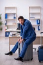 Young male employee preparing for trip at workplace Royalty Free Stock Photo