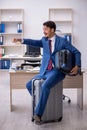 Young male employee preparing for trip at workplace Royalty Free Stock Photo