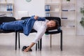 Young male employee sleeping in the office on chairs Royalty Free Stock Photo