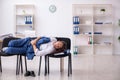 Young male employee sleeping in the office on chairs Royalty Free Stock Photo