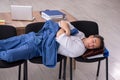 Young male employee sleeping in the office on chairs Royalty Free Stock Photo