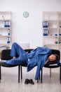 Young male employee sleeping in the office on chairs Royalty Free Stock Photo
