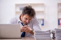 Young male employee and too much work in the office Royalty Free Stock Photo