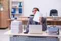 Young male employee unhappy with excessive work in the office Royalty Free Stock Photo