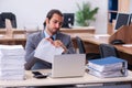 Young male employee unhappy with excessive work in the office Royalty Free Stock Photo