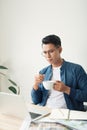 Young male engineer or accountant with pen and cup of coffee making calculations and notes in notebook in office Royalty Free Stock Photo