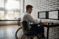 Creative people. Young male engineer or architect in a wheelchair working with two monitors, using stylus pen and Royalty Free Stock Photo