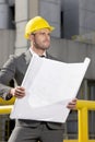 Young male engineer holding blueprint while looking away at construction site Royalty Free Stock Photo