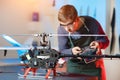 Young Male Engineer or Technician with Remote Control in His Hands Programs Drone. Focus on Drone. Royalty Free Stock Photo