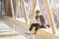 young male entrepeneur student waiting working on laptop in sunny corridor Royalty Free Stock Photo