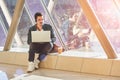 young male entrepeneur student waiting working on laptop in sunny corridor Royalty Free Stock Photo