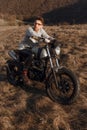 Young male in eyeglasses and gloves motorcyclist travels on motorbike, treveler and looking at a side in sunset time. Royalty Free Stock Photo