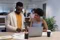 Young male and female african american business advisors discussing over document at workplace