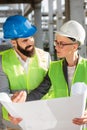Young male and female architects or business partners discussing floor plans on a construction site, facing each other Royalty Free Stock Photo