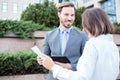 Happy young male and female business people talking in front of an office building, having a meeting and discussing Royalty Free Stock Photo