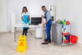 Young Male And Female Cleaners Cleaning Office Royalty Free Stock Photo