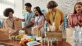 Young male and female volunteers packing food and drinks donation for homeless into boxes and paper bags, Small group of Royalty Free Stock Photo