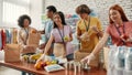 Young male and female volunteers packing food and drinks donation for homeless into boxes and paper bags, Small group of Royalty Free Stock Photo