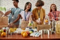 Young male and female volunteers packing food and drinks donation for homeless into paper bags, Small group of happy Royalty Free Stock Photo