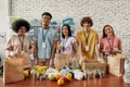 Young male and female volunteers smiling at camera while packing food and drinks donation into paper bags and box, Small Royalty Free Stock Photo