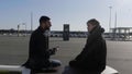 Young male friends sitting on a bench at bus stop and talking. HDR. Two men waiting for a bus outdoors during Royalty Free Stock Photo