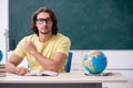 Young male geography teacher in front of blackboard