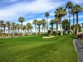 A young male golfer walking towards the green on a par 4 surrounded by water and palm trees in the background on the desert oasis Royalty Free Stock Photo