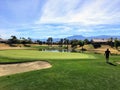 A young male golfer walking towards the green on a par 4 surrounded by water and palm trees in the background on the desert oasis Royalty Free Stock Photo