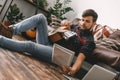 Young guitarist hipster at home sitting on the floor with guitar reading notes Royalty Free Stock Photo