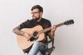 Young guitarist hipster at home with guitar on the chair isolated