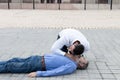 Young male helping an unconscious man outdoors - first aid concept