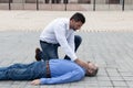 Young male helping an unconscious man outdoors - first aid concept