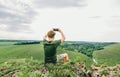 Young male hiker sits on top of a mountain and takes a photo of beautiful landscape on smartphone. Young man sits on a mountain Royalty Free Stock Photo