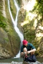 Young tourist camping with backpack near a waterfall in forest. Royalty Free Stock Photo