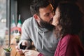 A young male hipster with a beard suggests marrying a girl in a cafe, hugging and kissing