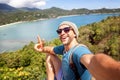 Young male hipster traveler doing selfie overlooking the tropical sea. Adventure, vacation, wonderlust, internet, technology Royalty Free Stock Photo