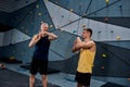 Young male instructor and cheerful middle aged man smiling, warming up bodies, while preparing for climbing in
