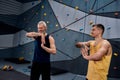 Young male instructor and middle aged man smiling, warming up bodies, while preparing for climbing in bouldering center