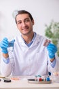 Young male lab assistant in drug synthesis concept