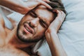 Young male lay in bed with terrible head pain