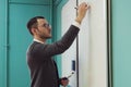 Young male lecturer writes on whiteboard in classroom
