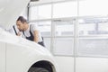 Young male maintenance engineer repairing car engine in workshop