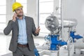 Young male manager in hard hat using cell phone by machinery in industry Royalty Free Stock Photo